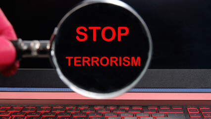 Stop Terrorism text through a magnifying glass on a black monitor. The concept of peace and the...
