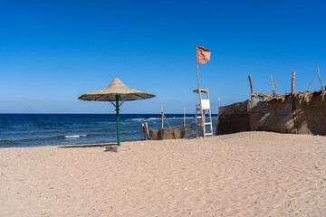 Bad condition reed umbrella and lifeguard chair at the beach
