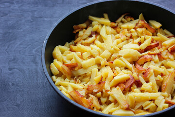 fried potatoes in a frying pan on a dark background.