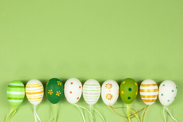 A row of painted multi-colored eggs in a row on a green background. View from above. Place for...