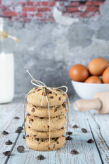 Stack of biscuits tied with string. Typical American Cookie with chocolate chips. Bottom decorated with milk bottle, rolling pin, eggs, chocolate chips and flour.