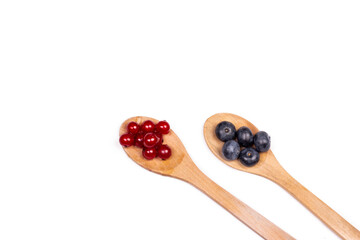 Blueberry and red currant with wooden spoon on white background.