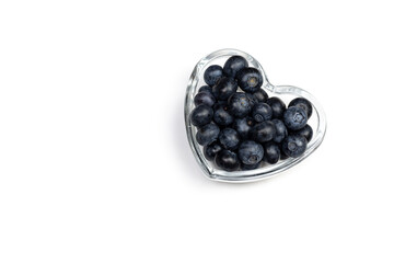 Ripe fresh blueberry in heart shaped plate on white background.