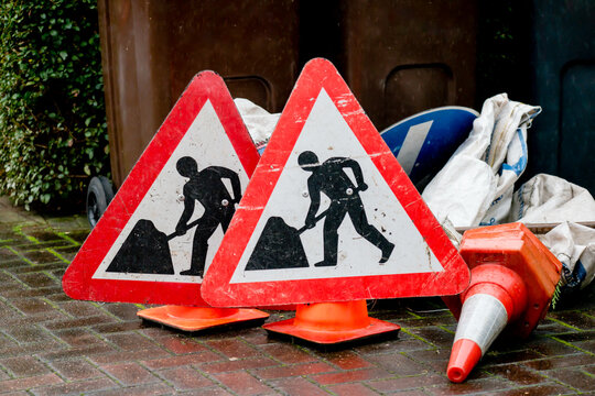 Men at Work signs, traffic cones and signage in domestic garden