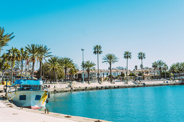 Beautiful sea promenade with boats and palm trees. 