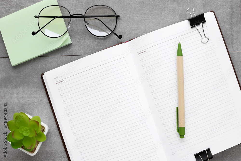 Poster a green plant and a green pen on an open notepad with space for text and a calculator. view from abo