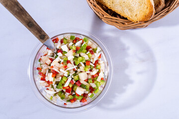 Top view of a classic bell pepper and onion vinaigrette with vinegar and olive oil in a transparent bowl. Healthy and natural food.