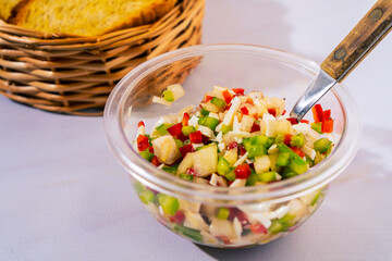 A classic bell pepper and onion vinaigrette with vinegar and olive oil in a transparent bowl and a...