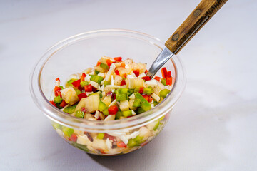 High view of a typical bell pepper and onion vinaigrette with vinegar and olive oil in a transparent bowl. Healthy and natural food.