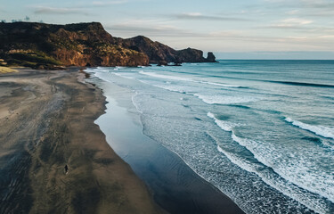 Aerial drone view of girl walking on the vast Bethells Beach