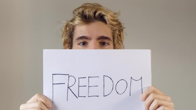 Adult Young Man Holding A Paper Message With The Text Freedom, protect our democracy concept, 4k resolution
