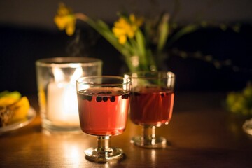 Two glasses of drink, wine, juice, still life candles and dinner, on a wooden table with candle and wine grapes in the background