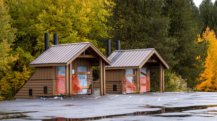Pair of closed vault toilet buildings located along a parking lot