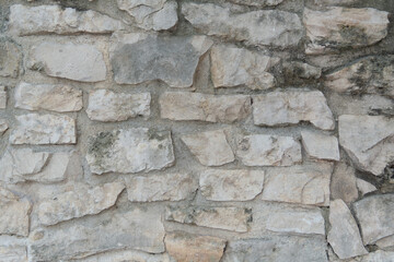Natural stone wall. Gray stone background. A wall of stones of various sizes filled with cement.