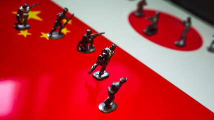The concept of the economic and political crisis between Japan and China, toy soldiers attacking each other against the background of national flags.