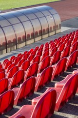 Fototapeta premium red benches of soccer - athletic stadium, sun set, place for spectators and athletes