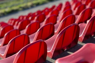 Fototapeta premium red benches of soccer - athletic stadium, sun set, place for spectators and athletes