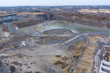 Heavy mining dump trucks driving along the opencast of excavator loads the mined rock in the dump truck