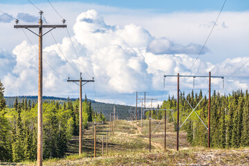 Power lines seen in a rural, country area in Canada with mountains in the background during...