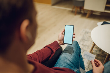 Man hands with smartphone and credit card while online shopping at home