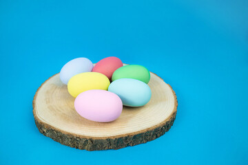 Easter, plain, multi-colored eggs on a hemp plate on a blue background. The concept of holiday, religion, customs, egg coloring . High quality photo
