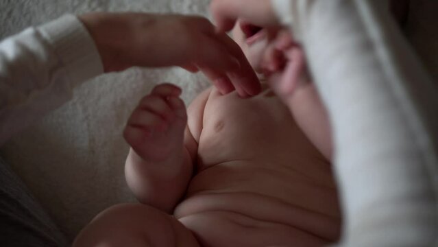 Newborn Baby And Young Mom Lie On Bed. Cute Smiling Teethless Kid Face Portrait. Woman Makes Massage Naked Child. Mother Care Of Babe. Infant, Mother Day, Childbirth, Beginning, Relationship Concept