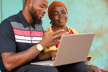 young african man using a laptop with an old african woman