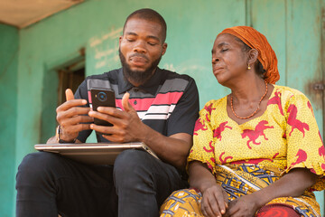young african man shows an old african woman content on a phone © Confidence