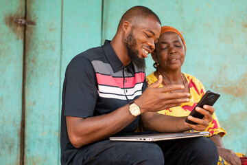 black man showing an old african woman content on his phone