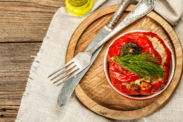 Homemade meat and rice stuffed bell peppers. Olive oil, sauce, cutlery on vintage wooden background