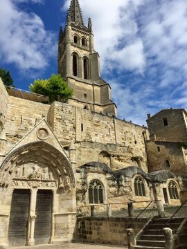 Saint Emilion, Bordeaux, France. Medieval monolithic church. Cobblestone, entrance, stone wall and bell tower. Saint Emilion is a commune in the Gironde department in southwestern France.