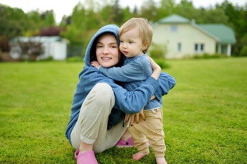 Fototapeta premium Cute big sister cuddling with her toddler brother. Adorable teenage girl holding baby boy. Children with large age gap. Big age difference between siblings.