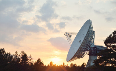 Large radio telescope. Dramatic sunset sky, glowing clouds. Nature, weather, science, equipment,...