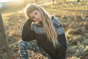 Obraz premium Lächelndes Gesicht: Ungezwungen spielt ein junges, hübsches, freundliches Mädchen im Abendlicht im Park. Sie hat schönes, langes, blondes Haar und bewegt sich in der Natur um gesund und fit zu bleiben