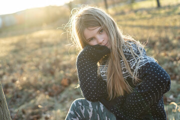 Lächelndes Gesicht: Ungezwungen spielt ein junges, hübsches, freundliches Mädchen im Abendlicht im Park. Sie hat schönes, langes, blondes Haar und bewegt sich in der Natur um gesund und fit zu bleiben