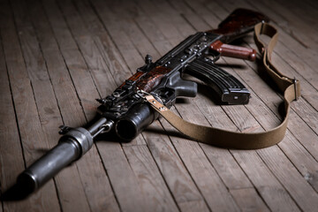 Close up of isolated Kalashnikov assault rifle with suppressor on wooden background