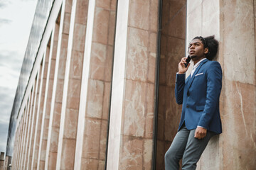 stylish african american businessman talking on the phone outside the office