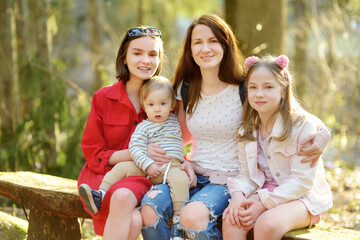 Fototapeta na wymiar Young mother and her three kids having fun during a hike in the woods on beautiful sunny spring day. Active family leisure with kids.