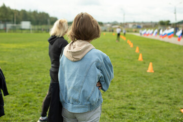 Girl looks at running dowry. Spectators at sports competition.