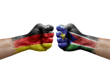 Two hands punch to each others on white background. Country flags painted fists, conflict crisis concept between germany and south sudan