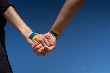 female hands painted in Ukraine flag colors yellow-blue holding. Stop the war and the power of...