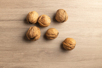 overhead shot of a group of organic walnuts on wooden table with side light