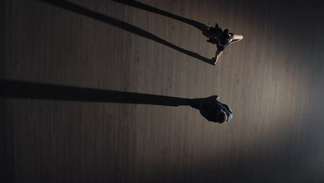 Top view of couple of dancers approach each other and begin to dance tango. Elements of latin ballroom dance in studio with gray background and dancing shadows. Slow motion ready, 4K at 59.94fps.