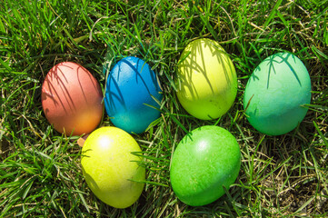Top view of a bunch of colorful Easter eggs laid out on the green spring grass. Flat style, Easter holiday concept.