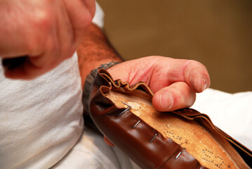Cobbler's hands, man crafting a shoe using cobbler's tools. Placing the skin in a last.