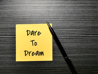Phrase dare to dream written on sticky note with a pen. - obrazy, fototapety, plakaty