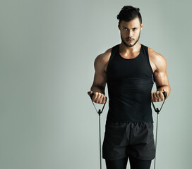 Im the master of my own fitness. Studio shot of a young man working out with a resistance band against a gray background. © Thurstan Hinrichsen/peopleimages.com