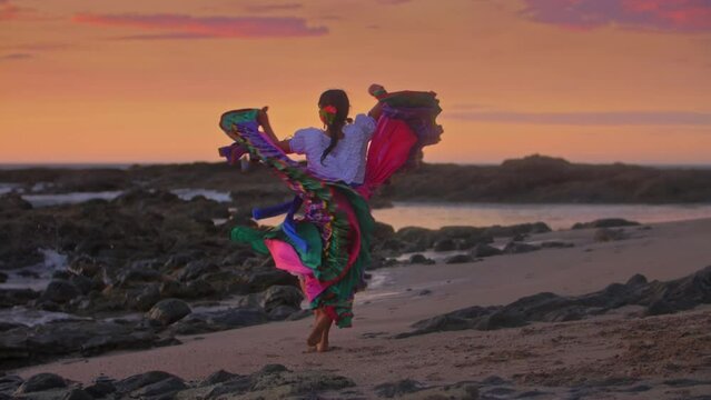 Slow motion video of Costa Rican woman in traditional Guanacaste dress dancing in sunset light at the beach