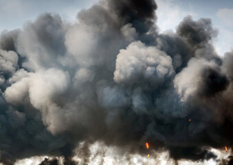 plumes of black smoke replace a blue sky after a huge explosian