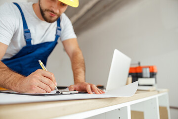 Close up of hands of repairman writing down details of an order on the clipboard while standing...